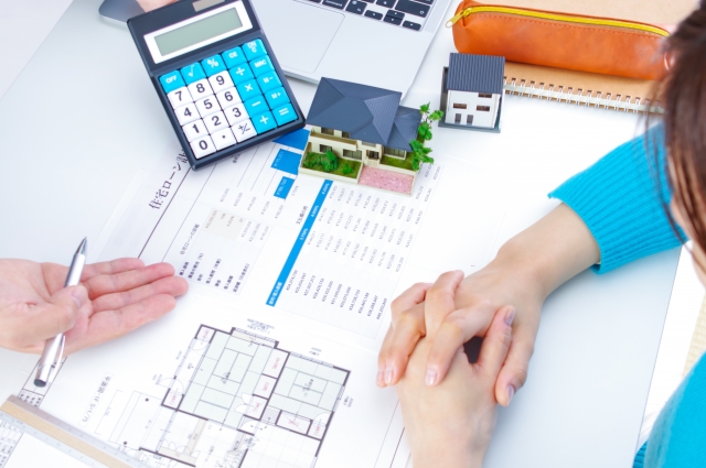 シングルマザーが住宅ローンや補助金の相談をしている様子。住宅の間取り図や見積書を前に、専門担当者と資金計画を確認している場面。